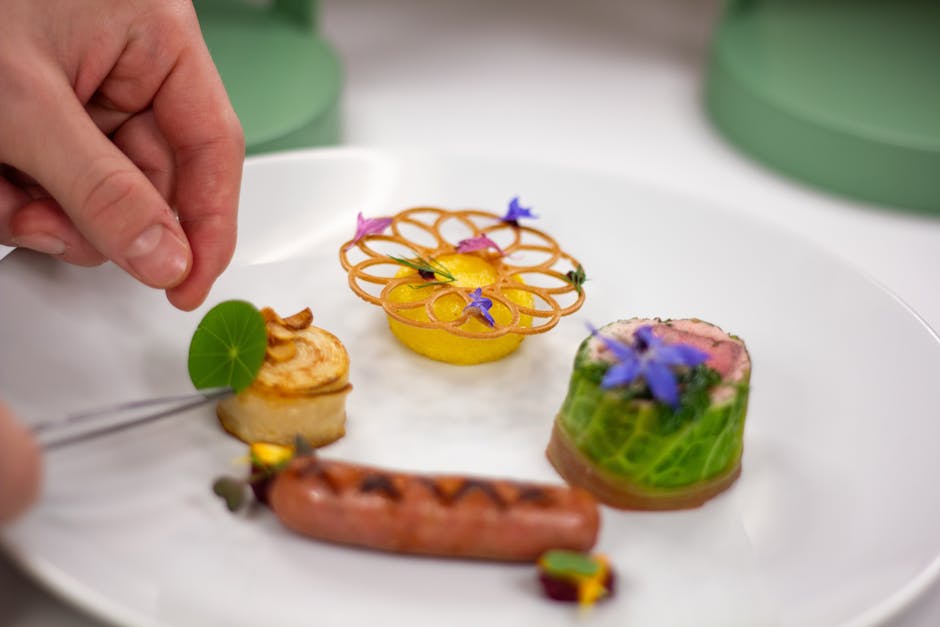 Chef using tweezers to plate a fine dining dish with precision