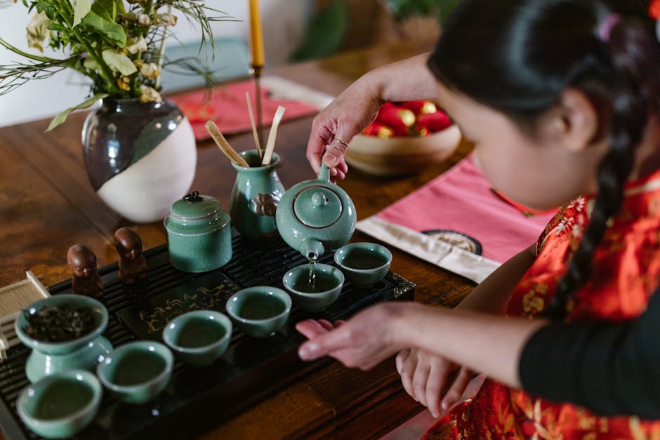 Traditional porcelain tea set with tea being poured slowly into a small cup